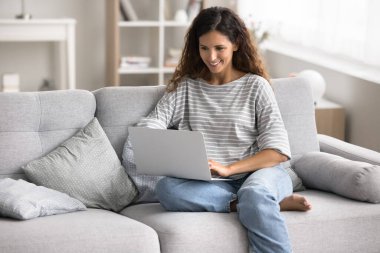 Kadınlar kanepeye modern dizüstü bilgisayarlarıyla oturur, kablosuz internet gezer, online alışverişin keyfini çıkarır, haberleri okur, çalışır veya uzaktan çalışır, bilgi araştırır, evdeki çevrimiçi derslere katılır.