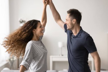 Aşık mutlu çift içeride dans edip eğleniyor. Sevgili kocanın elini tutması, en sevdiği müziğe taşınması, hafta sonunun tadını çıkarması, sıcak, modern oturma odasında birlikte vakit geçirmesi. Eğlence, ilişkiler