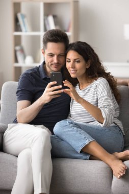 Hispanik eşler rahat bir koltukta dinlenip cep telefonu ekranına bakıyorlar, internette sörf bilgileri alıyorlar, bilet alıyorlar, otel ayırtıyorlar, yeni modern uygulamaların tadını çıkarıyorlar, kablosuz internet kullanarak iletişim kuruyorlar. Teknoloji