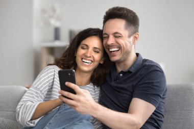 Gülen milenyum eşleri evdeki koltukta oturup mutlu haberler okuyor, komik online içeriklere gülüyor, internette akıllı telefon kullanarak boş vakitlerini geçiriyorlar. Modern kablosuz teknoloji, yeni mobil uygulamalar kullanımı