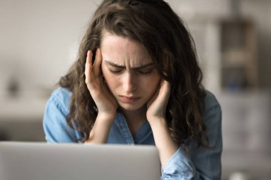 Dizüstü bilgisayarda çalışan yorgun bir kadın, ağır baş ağrısı, panik atak, aşırı bilgi yükleme, masaj, acıyı azaltmak, iş yükünden dolayı yüksek baskı, yakın görüş.