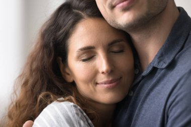 Sükûnetli, güzel İspanyol kadının yüz ifadesini kapat. Aşk anının tadını çıkar. Sıcaklık, okşama, sarılma, gözleri kapalı koca. Saf aşk, mutlu güçlü evlilik, genç eşler arasındaki güven ve destek.