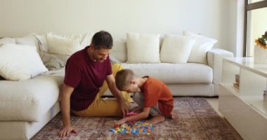 Sevimli küçük oğlan ve şefkatli Latin baba evde inşaat oyunu oynuyorlar renkli yapı taşlarını alıyorlar, konuşuyorlar, gülüyorlar, aile eğlencelerinden, oyun zamanlarından, babalıktan zevk alıyorlar.