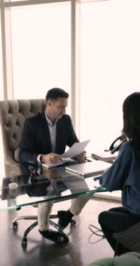 Genç kadın başvuru sahibi işe alınmaz masa başına oturur, el sıkışır, erkek İK yöneticisine saygılarını sunar, iş görüşmesini başarıyla tamamlar, dikey bir bakış açısıyla. İnsan kaynakları, şirket personeli, kelle avcılığı.