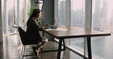 Modern ofiste tek başına çalışan Latin iş kadını laptop kullanıyor, satış verilerini analiz ediyor, mali raporları kontrol ediyor, piyasa araştırmaları yapıyor, analizleri gözden geçiriyor, masadaki sunumlarda düzeltmeler yapıyor.