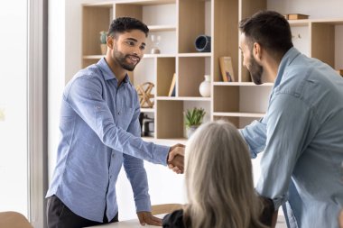 Olumlu genç Arap işadamı iş ortağıyla toplantı masasında tokalaşıyor, konuşmayı bitiriyor, müzakere ediyor, takım çalışmasını, ticareti, güveni tartışıyor. Hoş geldin ekibi çalışanı.