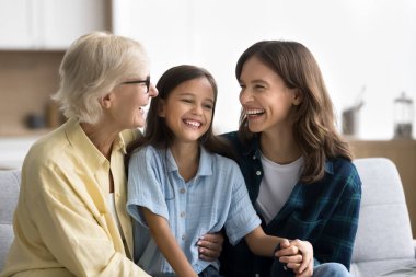Neşeli genç anne ve son sınıf anneannesi küçük kızı kucaklıyor, çocuğu gıdıklıyor, gülüyor, kıkırdıyor, aile eğlencesinden hoşlanıyor, yakın ilişkiden zevk alıyor. Üç neslin mutlu kızları ve kadınları evde eğleniyor.