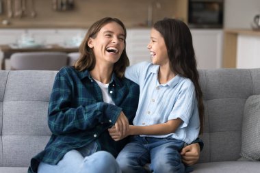 Neşeli anne ve tatlı küçük kız evdeki kanepede sarılıp eğleniyorlar, gıdıklanıyorlar, şakalar yapıyorlar, bağ kurmaktan zevk alıyorlar, yakın ilişkiler, annelik, çocukluk.