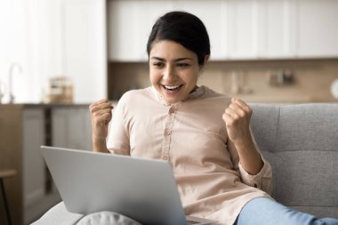 Aşırı neşeli Hintli kadın dizüstü bilgisayarında inanılmaz haberler okuyor, çok mutlu hissediyor, banka kredisi onayı alıyor, ticari teklifler alıyor, evet hareketi yapıyor, iş tanıtımını kutluyor, başarı dolu anı kutluyor. Zafer, kazanmak.