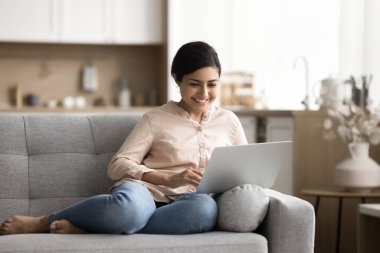 Kanepede dinlenen Hintli bir kadın internette boş vakitlerini arkadaşlarıyla sohbet ederek, haber akışı yaparak, gönderileri okuyarak, abonelik bazlı internet hizmetleri aracılığıyla online yayınlar izleyerek geçiriyor.