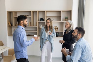 Çok ırklı ofis arkadaşları iş yerinde tatilin tadını çıkarıyorlar, birlikte sıcak kahve içiyorlar, iş, kariyer, çay eşliğinde projeler tartışıyorlar, çevrimdışı iletişimin keyfini çıkarıyorlar.