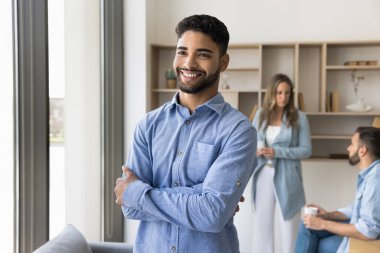 Mutlu, kendine güvenen genç Arap işadamı elleri bağlı bir şekilde poz veriyor, ofis toplantı odasında dikiliyor, dişlek bir gülümsemeyle gözlerini kaçırıyor, çeşitli şirketlerde kariyer yapmaktan keyif alıyor. Gizli çekim.