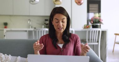 Çekici Latin kadın dizüstü bilgisayar kullanarak kanepede oturuyor. Ailesiyle, arkadaşıyla video görüşmesine katılıyor. Profesyonel danışmanlık alıyor, düşüncelerini paylaşıyor.