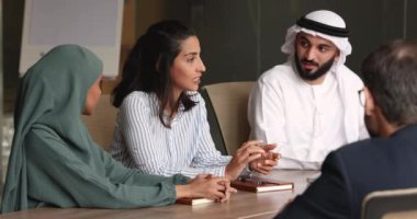 Masada Arap iş ortaklarıyla konuşan pozitif İspanyol iş kadını beyin fırtınası, takım çalışması, konuşma, el sıkışma gibi yaratıcı fikirler sunuyor. Çeşitli takımlar işbirliğini tartışıyor