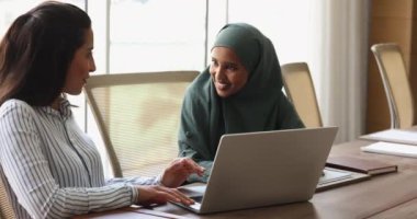 İki mutlu Arap ve Latin iş arkadaşı birlikte dizüstü bilgisayarda proje üzerinde çalışıyor, konuşuyorlar, takım çalışması fikirleri üzerinde kafa patlatıyorlar, uygulama, yazılım ve çevrimiçi sunumu tartışıyorlar.