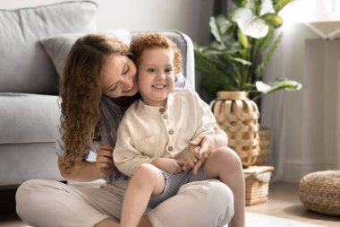 Genç anne, güneşli, rahat bir oturma odasında, sıcak zeminde oturan, boş zamanlarını, iletişim kuran, aşkı hisseden, sıcaklığını ve şefkatini ifade eden küçük çocukla paha biçilemez bir zaman geçirmekten hoşlanıyor. Mutlu annelik