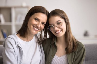 Mutlu bir annenin portresi genç kızıyla evde vakit geçirir, kanepeye oturur, kameraya bakar, gülümser, poz verir, sevgi gösterir, sıcak aile ilişkilerinin keyfini çıkarır, hafta sonları iyi vakit geçirir.