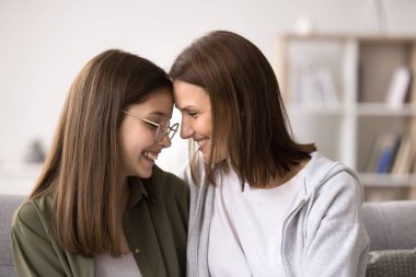 Sevgi dolu bir anne, genç kızıyla kanepeye oturur, şefkat, şefkat ve destek gösterir, evde birlikte paha biçilmez zaman geçirir, sıcak aile ilişkileri ve anlayış ile mutlu olur.