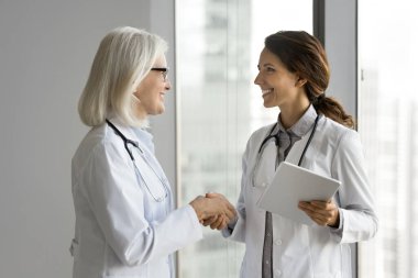 30 'lu yaşlardaki genç Latin ve 60' lı yaşlardaki Avrupalı kadın terapist meslektaşları beyaz önlük giyip, konferans veya seminerden önce el sıkışıyor, tanınıyor ve başarılı takım çalışmalarına saygı gösteriliyor.