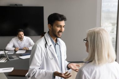 Toplantı odasında tartışan iki doktor. Hintli ve Avrupalı meslektaşlar görüşlerini paylaşıyor, genç bayan terapiste danışıyor, fikir alışverişinde bulunuyor, sorun çözmede işbirliği yapıyor