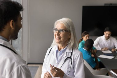 Orta yaşlı çekici dahiliyeci genç Hintli erkek stajyerle konferans odasında konuşma, seminer ya da konferans sırasında konuşma, eğitim eğitimine katılma. Fikir alışverişi