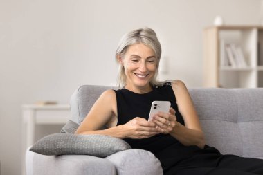 Modern akıllı telefonu kullanan gülümseyen kadın, videolar izliyor, aramalar, mesajlar ya da sosyal medya sohbetleri, internet parşömenlerine göz atmak, makaleleri okumak,