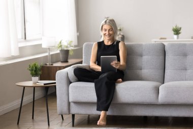 İnternet üzerinden video ya da video paylaşım platformu üzerinden video izleyen, dijital tablet kullanımını rahatlatan, ekommerce web sitelerine ve çevrimiçi mağazalara göz atan, evden rahatça alışveriş yapan bir kadın