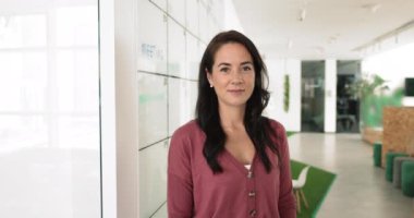 Genç bayan lise ya da üniversite öğretmeni ya da ofis çalışanı iş yerinde beyaz panoya yakın poz veriyor, gülümsüyor, kameraya bakıyor, kariyer başarısı ve başarılarından tatmin oluyor.