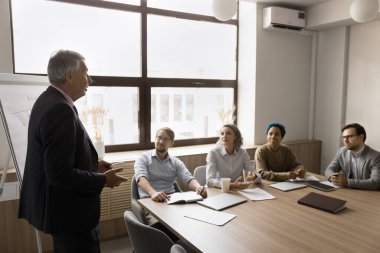 Takım elbiseli olgun işadamı, hissedarlarla resmi bir toplantı yaptı, modern yönetim kurulunda bir araya geldi, yeni kurumsal hedefler veya proje detayları sundu, fikir, strateji ve planı paylaştı, personel brifingi verdi