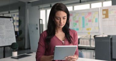 Şirin iş kadını, bölüm başkanı, dijital tablet kullanarak e-posta kutusunu kontrol ediyor. İşle ilgili iletişim kuruyor, şirket sohbetine cevap veriyor, online sunum üzerinde çalışıyor, raporları düzenliyor.