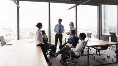 Modern ofis açık alanlarında çeşitli iş grupları beyin fırtınası yapıyor. Ekip lideri toplantıda çalışanlarla konuşuyor, işçilere talimat veriyor, fikirlerini paylaşıyor. Şirket danışmanı eğitmeni stajyerler.