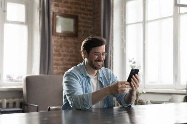 Yakışıklı iş adamı, modern akıllı telefon kullanarak çatı katında masa başında oturur, mesajları iyi ve hoş haberlerle okur, internette sörf yapar, boş zamanlarını internette geçirir. Teknik, iş uygulaması kullanım konsepti