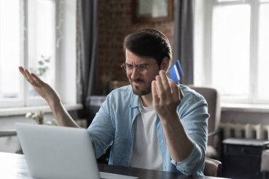 Adam dizüstü bilgisayarlı internet bankacılığı hizmeti ile masada oturuyor, engellenmiş kredi kartıyla, mali problemle, çek bakiyesiyle ilgili sıkıntılar var. İnternet dolandırıcılığı, başarısız maaş, para hırsızlığı, aşırı harcama