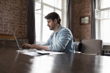 Laptop kullanan, bin yıllık iş adamı elinde kağıtlar ve hesap makinesiyle masada oturuyor. Muhasebe, finans yönetimi modern ofiste iş akışı, bütçe sayımı, fatura ödeme, yatırım planlama kavramı