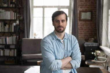 İş yerinde kollarını kavuşturmuş kendine güvenen bir iş adamı. Erkek girişimci ofisteki kamera görüntülerine bakar. Başarılı bir iş adamı ya da serbest çalışan portresi, kariyeri, mesleki mesleği olan kişi kavramı