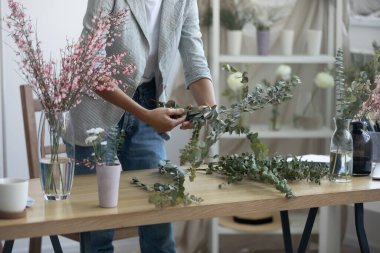 Dişi çiçekçiye yakın ürünler, bitkilerle ilgilenirler satılık çiçek süslemeleri yaparlar. Kadın iç mimar ev ofisinde el yapımı buketler düzenliyor. Bahçe işleri, dekor konsepti.