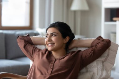 Gülümseyen, rüya gibi Hintli bir kadın evinde rahat rahat oturuyor, uzaktan bakan mutlu genç bir bayan, güzel bir geleceği hayal ediyor, başarıyı hayal ediyor, tembelce boş vakitlerin tadını çıkarıyor.