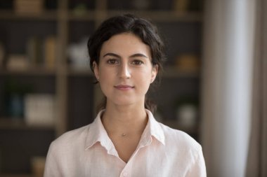 20 'li yaşlarda rahat bir oturma odasında tek başına dikilip kameraya bakan şık görünümlü bir kadın içeride kendine güvenen bir poz veriyor. Hizmetçi ya da emlakçı portresi konsepti