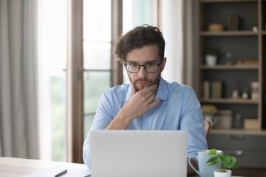 Çok düşünceli bir milenyum insanı yeni yapay zeka programı öğrenir, masaya oturur, dizüstü bilgisayara bakar, mesajı okur, bilgiyi gözden geçirir, modern bir cihaz kullanarak iş fırsatını değerlendirir.