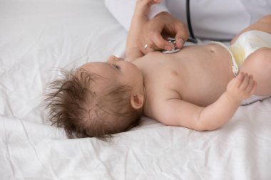 Bilinmeyen doktor steteskop tutuyor yeni doğan kalp atışlarını dinliyor, kapat. Pediyatrist, nefes kontrolü, bebek ciğerlerini düzenli olarak evde muayene ediyor. Sağlık hizmeti, tıbbi kontrol konsepti