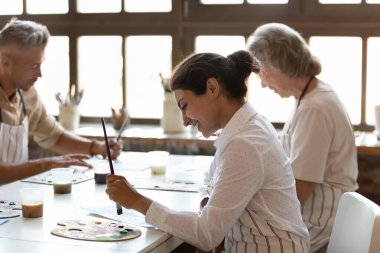 Çok ırklı ressamlar atölyede resim kursuna katılıyorlar. Hintli ressam elinde boya fırçası tutuyor masaya oturuyor, ilgileniyor ve ilham alıyor. Sanat terapisi, yaratıcı hobi, yaratılış konsepti