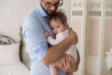 Önemseyen bir baba, tatlı bebeğini kollarına alıp sakinleştiriyor, yakın çekim yapıyor. Sevgi dolu bir baba şefkatli bir anın tadını çıkarır. Sevgisini ve şefkatini ifade eder. 0-6 yeni doğan bebeğe sarılır. Babalık, aile bağı kavramı