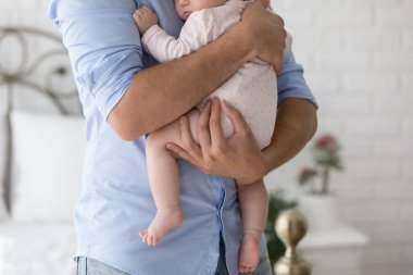 Being father, happy fatherhood, cherish, protection concept. Cropped shot unknown young dad holds on arms, lulls his 0-6 newborn baby daughter, calming before daytime nap feeling unconditional love clipart