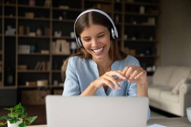Kulaklıklı kadın gülümsüyor dizüstü bilgisayar ekranına bakıyor ders çalışıyor, müzik dersini dinliyor uzaktan etkili internet ve modern kablosuz teknolojinin tadını çıkarıyor. Video çağrısı etkinliği, eğitim kavramı