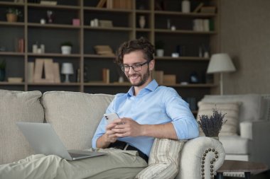 Adam kanepede dizüstü bilgisayarı ve akıllı telefonu ile dinleniyor. Mutlu milenyum adamı rahat koltukta rahat rahat oturuyor kucağında kablosuz bilgisayarla mesajları paylaşıyor, mesajları okuyor, gülümsüyor keyfine bakıyor ve sohbet ediyor.