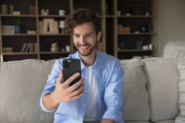 Mutlu 35. yüzyıl adamı cep telefonu ekranına bakıyor, video görüşmesinden zevk alıyor, modern teknoloji ve uygulamaları kullanarak internet üzerinden iletişim kuruyor, evde tek başına vakit geçiriyor, yurt dışında yaşayan ailelerle hoş sohbetler ediyor.