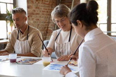 Kağıt üzerinde akrilik boyalarla resim yapan üç yaşlı ve genç sanat okulu öğrencisi, grup sınıfında yaratıcı bir hobi edinmiş gibi görünüyorlar. Yetenekleri geliştir, mesleki sanatsal eğitim kavramı kazan