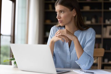 Çekici, ciddi, düşünceli bir iş kadını. Masasında, derin düşüncelere dalmış kablosuz bilgisayarla uzaklığı gözetliyor. Telework modern teknoloji, çözüm ve yaratıcı fikir arayışı kavramını kullan