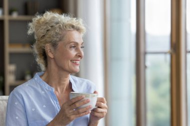 Güzel, huzurlu, yaşlı bir kadın kanepeye oturmuş gülümsüyor. Gözlerini kaçırıyor, fincanı tutuyor, sabah kahvesini içiyor ya da canlandırıcı bir çay içiyor. Boş vakitlerini modern oturma odasında yalnız geçiriyor. Rahatlama, hayal kurma