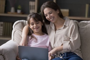 Bilgisayarı ve abonelik hizmetlerini kullanarak internetten film izleyen anne ve kız çocuklarına gülmek, bilgisayar ve internet kullanarak videonun keyfini çıkarmak, oturma odasındaki kanepede dinlenmek. Modern teknoloji kullanımı boş vakitlerde